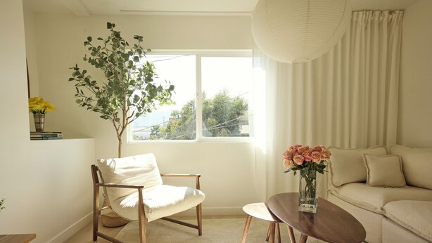 A living room with a wooden chair, a small round table, a sofa, a potted plant, and a window with curtains. - Brand new community- Prime Highland Park! Unit 2 (Los Angeles)