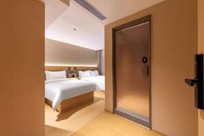 Une chambre d’hôtel avec deux lits, un grand miroir, une porte à clé et un téléviseur fixé au mur.