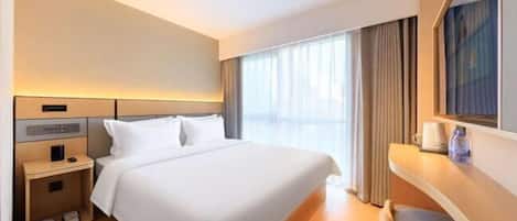 A hotel room with a bed, bedside table, and a chair.