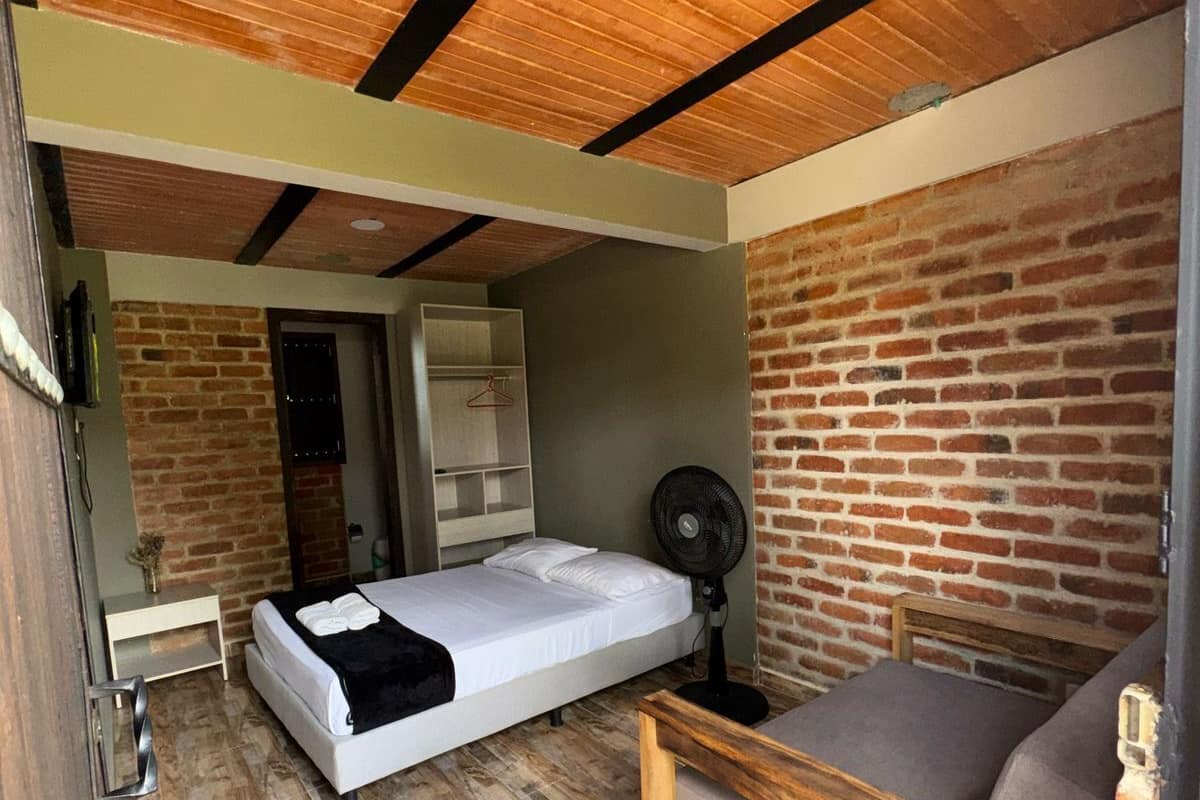 A compact room with a bed, a small table, and a fan.