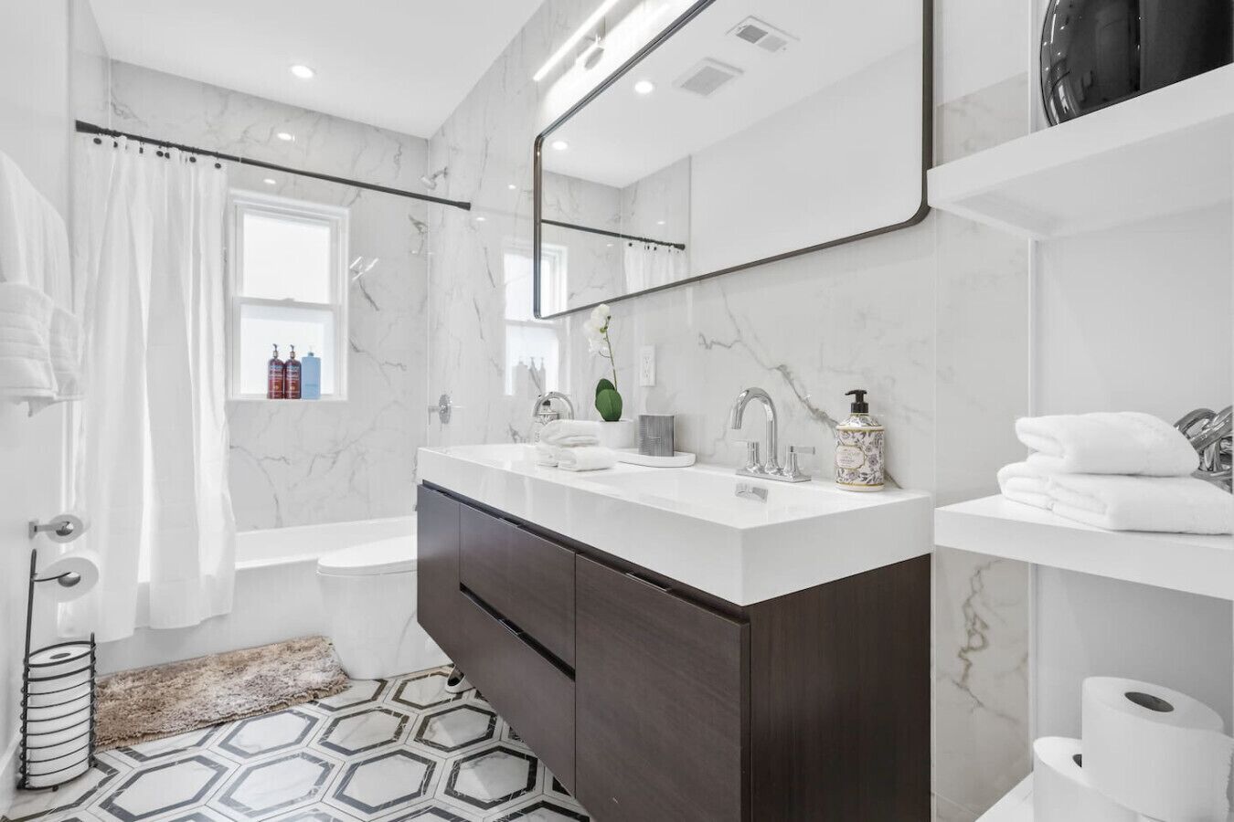 Un baño moderno con lavamanos doble, un espejo grande y zona de ducha.