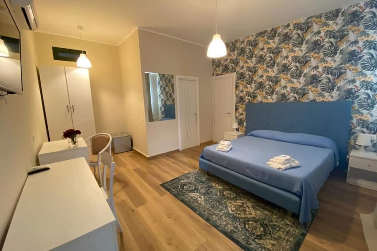 A bedroom with a bed, a desk, and a chair.