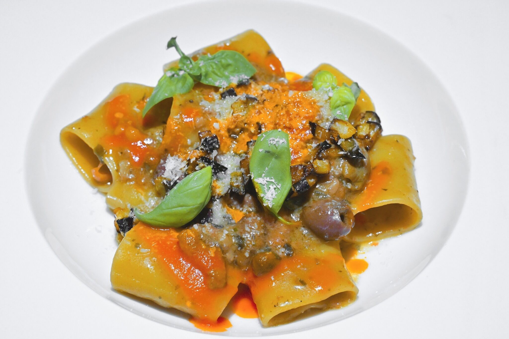 Eine Pasta-Platte mit Tomatensauce, garniert mit Basilikum und geriebenem Käse.