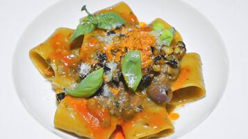 Eine Pasta-Platte mit Tomatensauce, garniert mit Basilikum und geriebenem Käse.