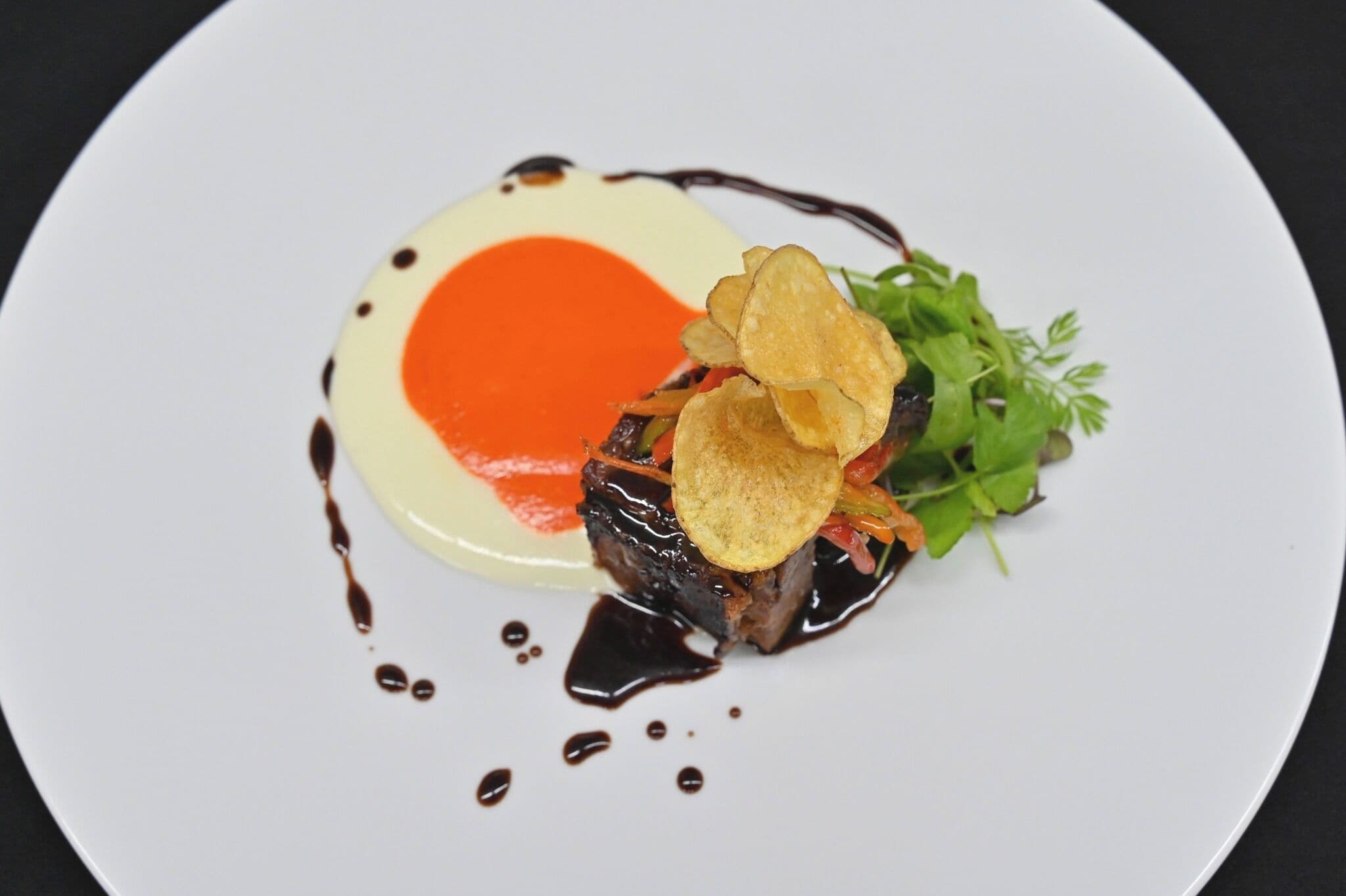 Ein weißer Teller mit einem Gericht aus Fleisch, Pommes und Salat.