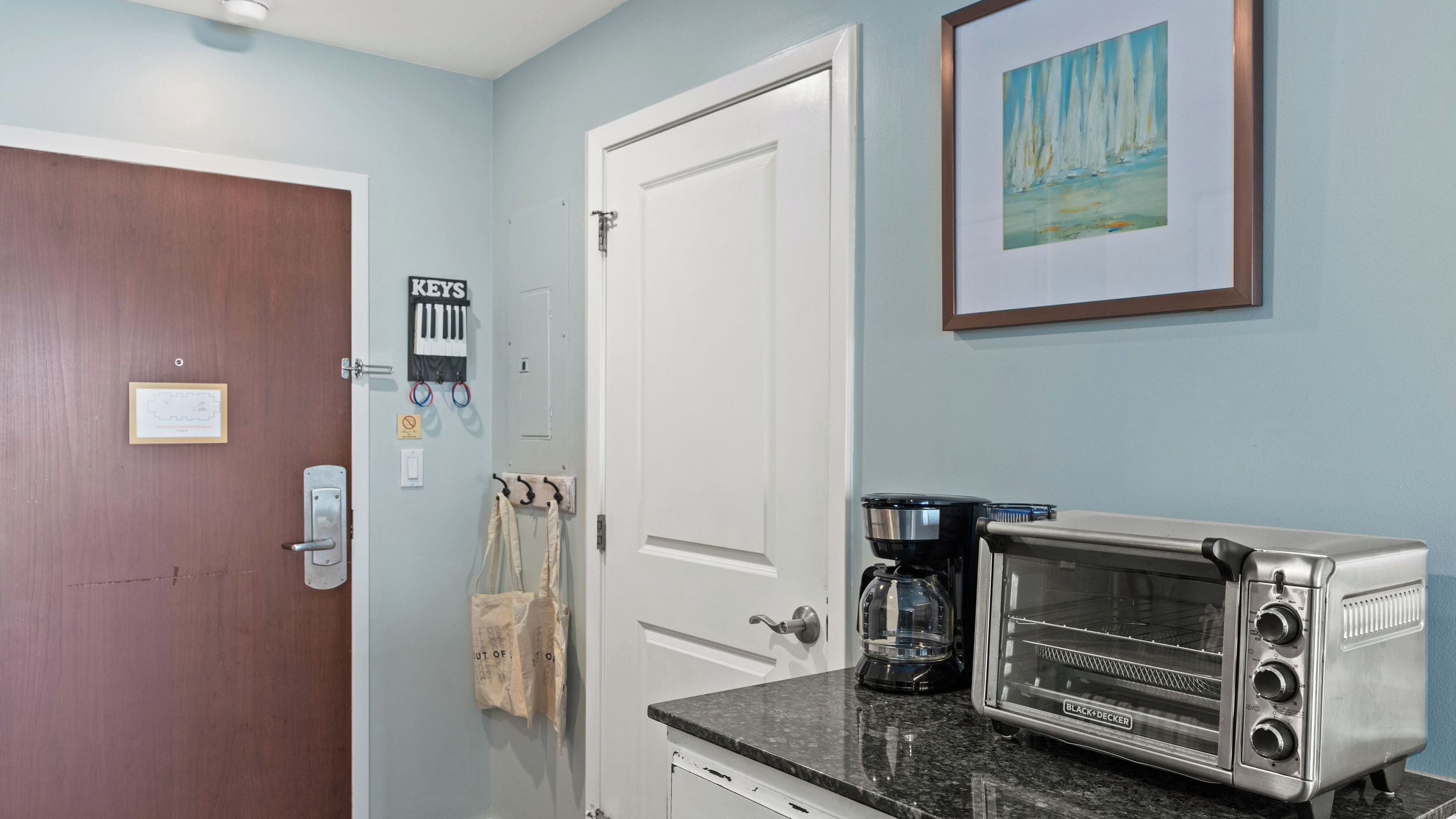 Una cocina con tostadora, cafetera y una puerta con un cartel que dice 'KEYS'.