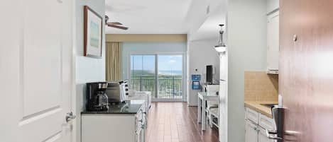 A modern kitchen with a large window, a coffee maker, and a dining area with a table and chairs.