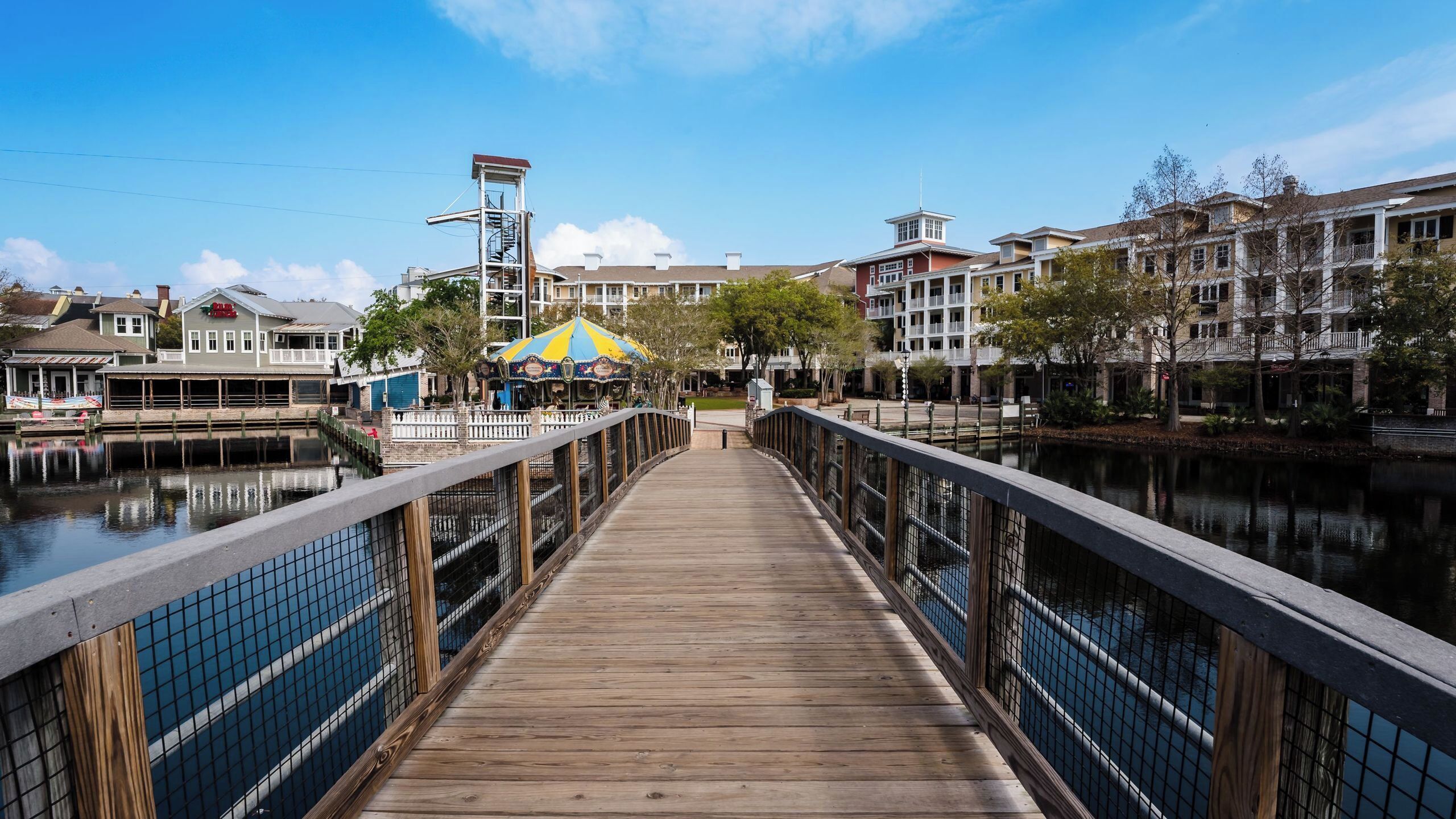 A wooden boardwalk leading to a building with a yellow and blue striped awning.