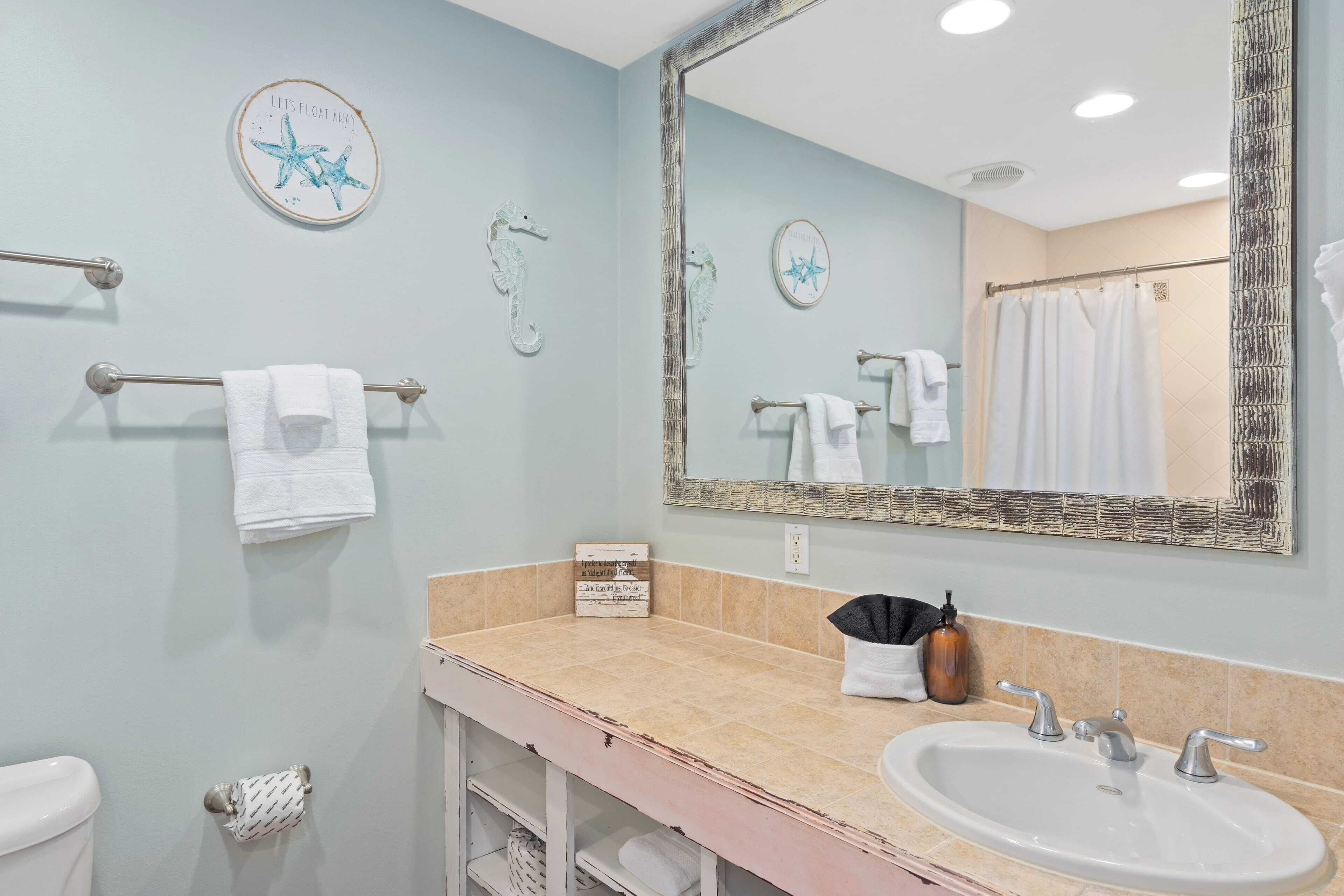 Un baño con un espejo grande, un lavabo y toalleros.