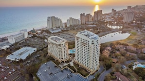 A high-rise hotel with a pool, surrounded by a parking lot and a body of water. - Miramar Beach Studio w/ Pool, Tennis & Walk to Beach Luau Eastern Sky (Miramar Beach)