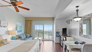 A hotel room with a bed, a desk, a chair, a ceiling fan, a TV, and a balcony with a view. - Miramar Beach Studio w/ Pool, Tennis & Walk to Beach Luau Eastern Sky (Miramar Beach)