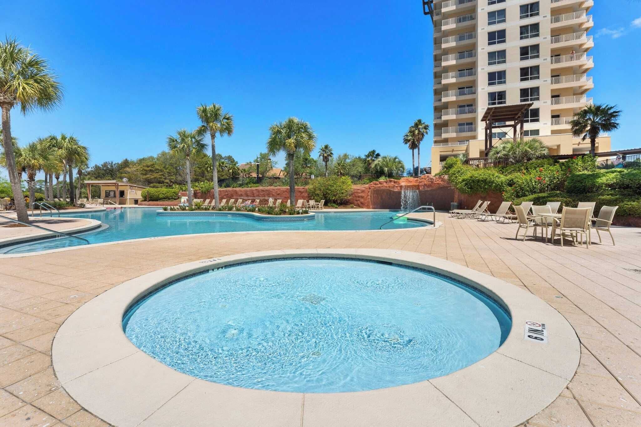 A pool area with multiple swimming pools, lounge chairs, and palm trees.
