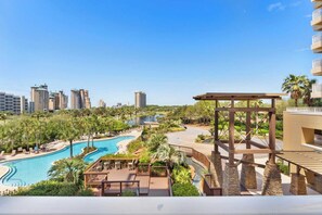 A resort with a large swimming pool, palm trees, and a view of tall buildings in the background. - Miramar Beach Studio w/ Pool, Tennis & Walk to Beach Luau Eastern Sky (Miramar Beach)
