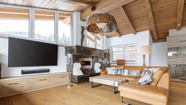 A spacious living room with a large flat-screen TV, a fireplace, a sofa, and a wooden ceiling. - Penthouse Near Mittersill (Mittersill)