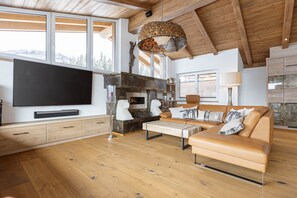 A spacious living room with a large flat-screen TV, a fireplace, a sofa, and a wooden ceiling. - Penthouse Near Mittersill (Mittersill)