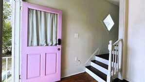 A room with a pink door, a staircase, and a window. - The Historic Darling House + Hot tub in Downtown Savannah!  Great for Groups! (Savannah)