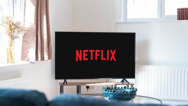 A television with the Netflix logo on a stand in a room with a window, a radiator, and a vase with dried flowers. - Stylish 4 Bedroom Spacious House w/ Parking - Sleeps 10 - Families & Contractors (Broad Oak)