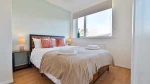 A bedroom with a bed, bedside lamps, a window, and a radiator. - Stylish 4 Bedroom Spacious House w/ Parking - Sleeps 10 - Families & Contractors (Broad Oak)