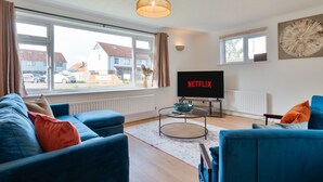 A living room with a large window, a flat-screen TV, and a sofa. - Stylish 4 Bedroom Spacious House w/ Parking - Sleeps 10 - Families & Contractors (Broad Oak)