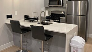 A modern kitchen with a central island, stainless steel appliances, and bar stools.