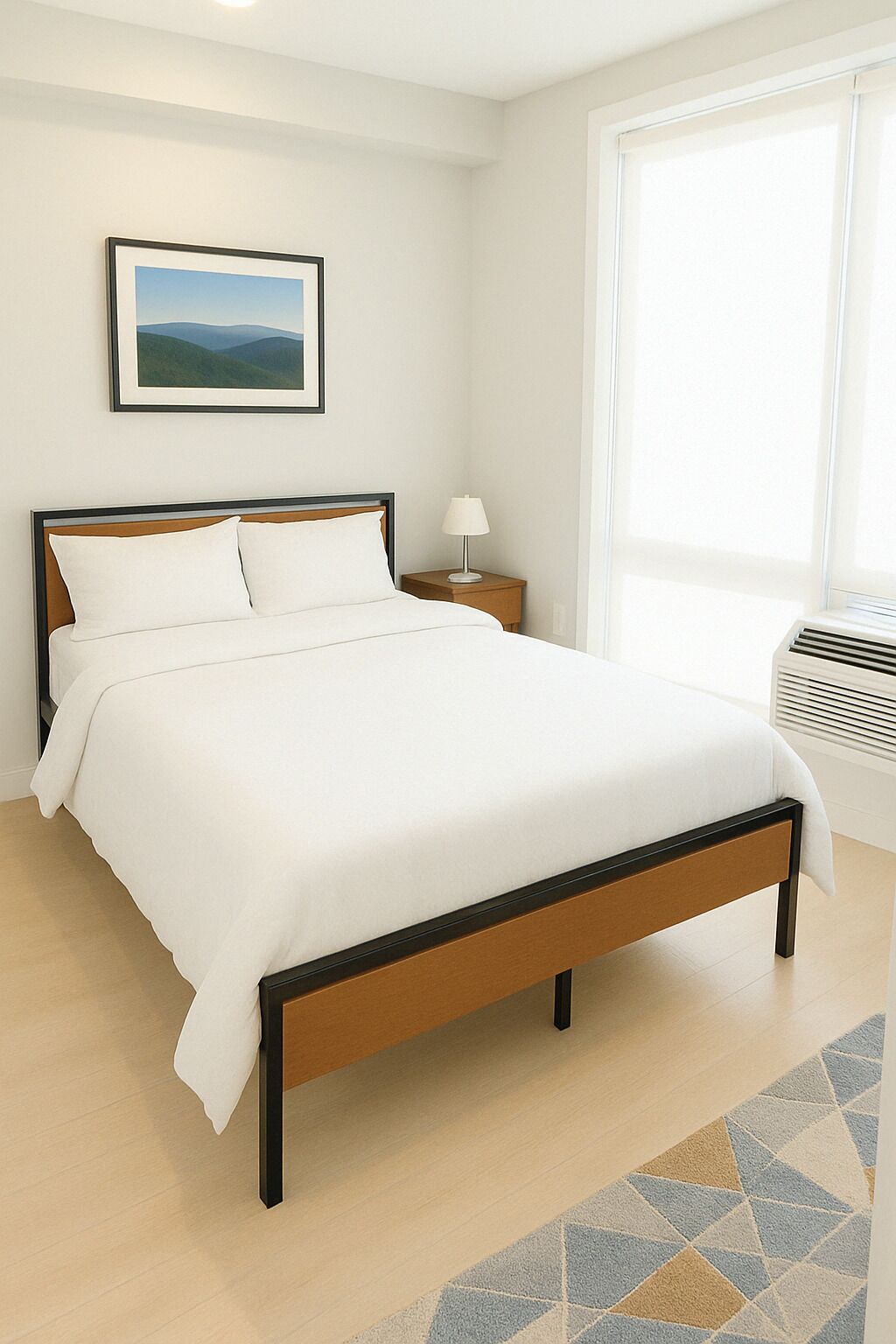 A neatly made bed with a wooden frame and white bedding, a bedside table with a lamp, a framed picture on the wall, and a large window with blinds.