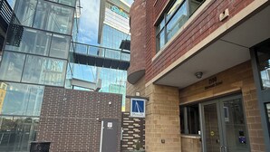 Un edificio moderno con facciata in vetro, ingresso in mattoni e una segnaletica che indica un luogo.