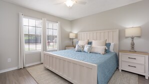 A bedroom with a bed, bedside tables, a ceiling fan, and a window with curtains. - Live Oak Hideaway Enjoy Beaches, Dining & Shopping (Gulf Breeze)