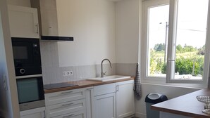 Una cocina moderna con armarios blancos, encimera de madera, horno integrado y ventana con vistas a zonas verdes.