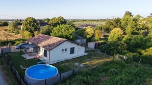 Una casa con piscina, rodeada de follaje y un cielo despejado.