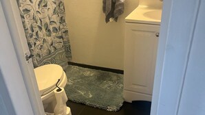 A bathroom with a toilet, a sink, and a shower curtain with a floral pattern. - Cozy North Valley Charm (Albuquerque)