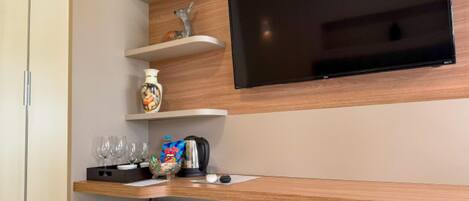Eine moderne Küchenzeile mit integriertem Fernseher, Holzregalen und einem kompakten Kühlschrank.