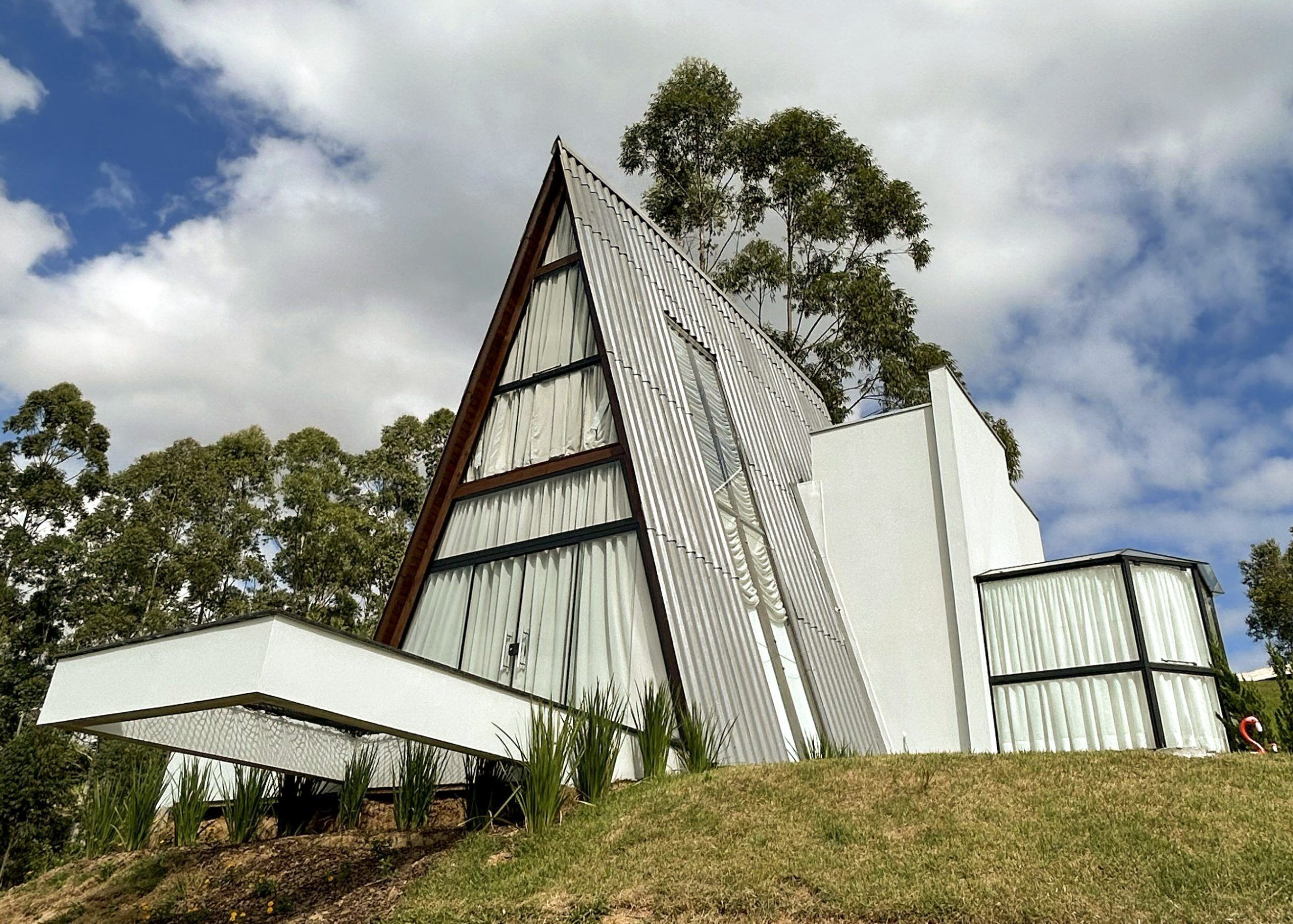 Un edificio moderno con techo triangular, ventanas grandes y una extensión de techo plano.