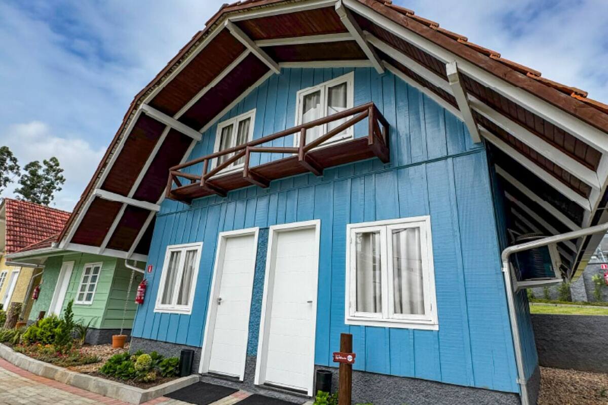 Una casa blu con tetto a falde, due porte bianche e un balcone in legno.