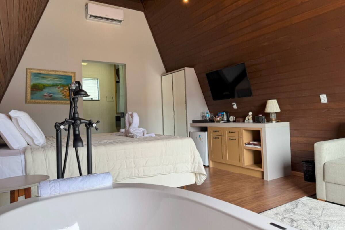 Una camera da letto con un letto, una scrivania, una sedia, una TV e un quadro appeso al muro.