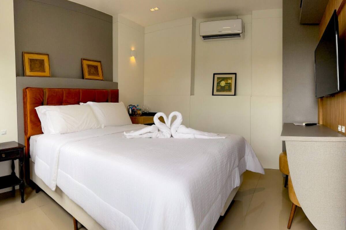 Una camera d'albergo con un letto rifatto, una scrivania e un televisore.