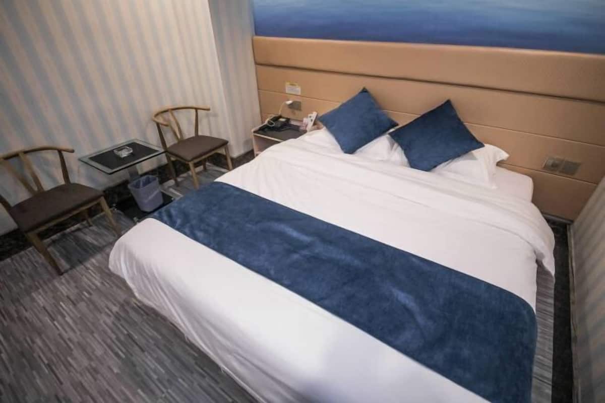 A hotel room with a bed, a desk, a chair, and a nightstand.