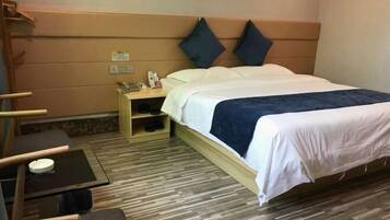 A hotel room with a bed, a nightstand, a chair, a small table, and a shoe rack.