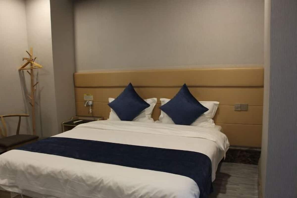 A hotel room with a bed, a nightstand, a lamp, and a chair.