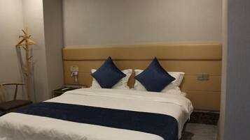 A hotel room with a bed, a nightstand, a lamp, and a chair.
