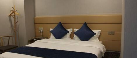 Une chambre d’hôtel avec un lit, une table de chevet, une lampe et une chaise.