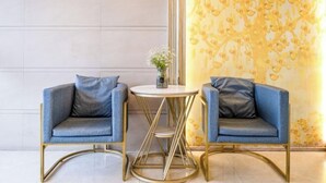 Una habitación moderna con dos sillones azules y una mesita redonda con un florero.