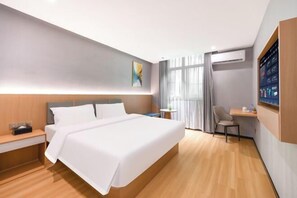 Een moderne hotelkamer met een groot bed, nachtkastje, bureau en uitzicht op de stad.