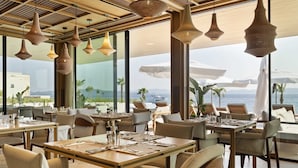 A restaurant with tables set for dining, large windows offering a view of the sea, and hanging pendant lights. - Villa Massima Prima with Pool (Ugljan)