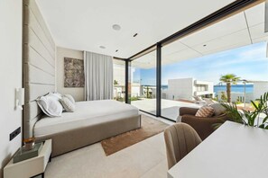 Une chambre moderne avec un grand lit, un bureau et une vue sur la mer.