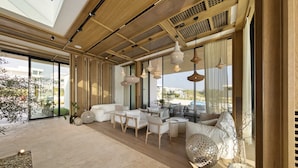 A spacious living area with a high ceiling, large windows, and a view of the outdoors.