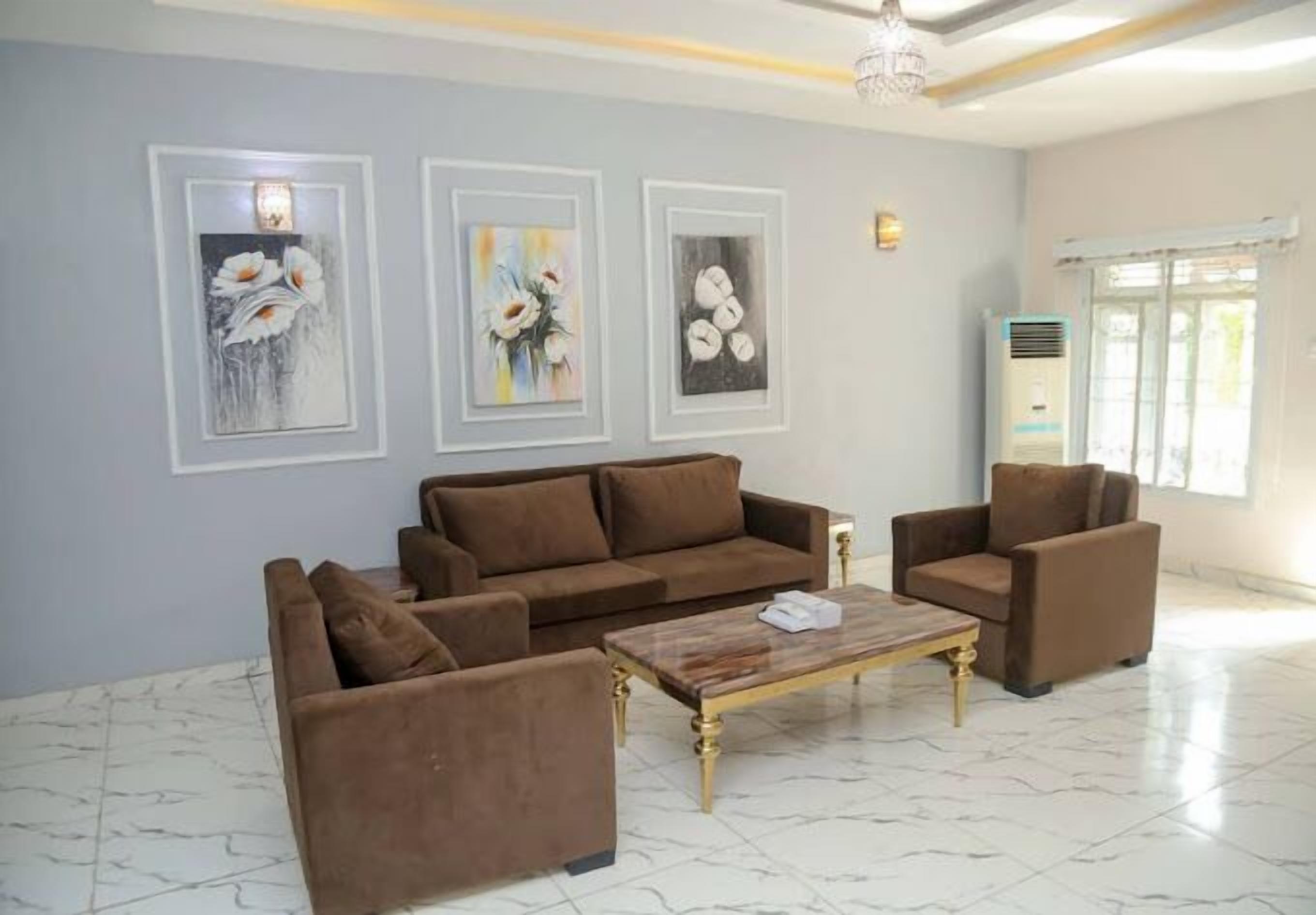 A living room with a brown sofa set, a coffee table, and three framed artworks on the wall.