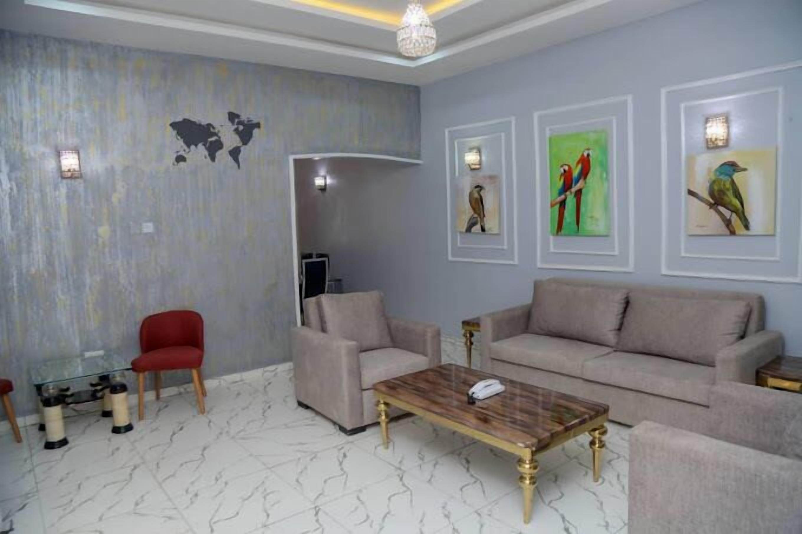 Ein Wohnzimmer mit einem beigen Sofa, einem roten Sessel, einem Glastisch und einer Weltkarte an der Wand.