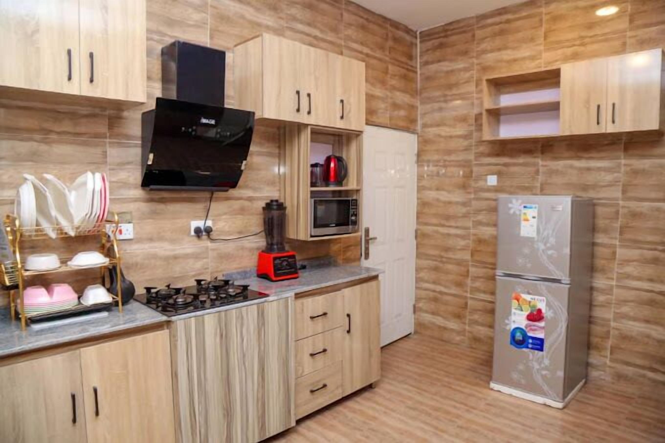 Una cocina moderna con armarios de madera, microondas, estufa a gas y refrigerador.