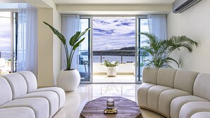 A modern living room with a large window, two sofas, a coffee table, and potted plants. - 6B Exclusive Oceanfront Retreat,High-End Apartment (Panama City)