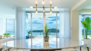 A modern dining area with a glass table, white chairs, and a view of the sea. - 6B Exclusive Oceanfront Retreat,High-End Apartment (Panama City)